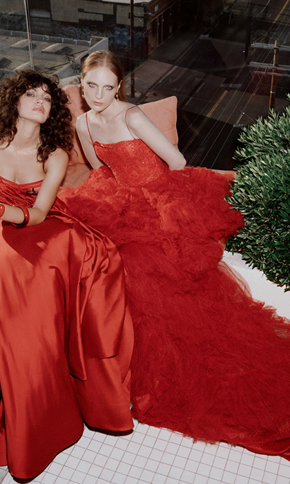 Two women in red gowns sitting down