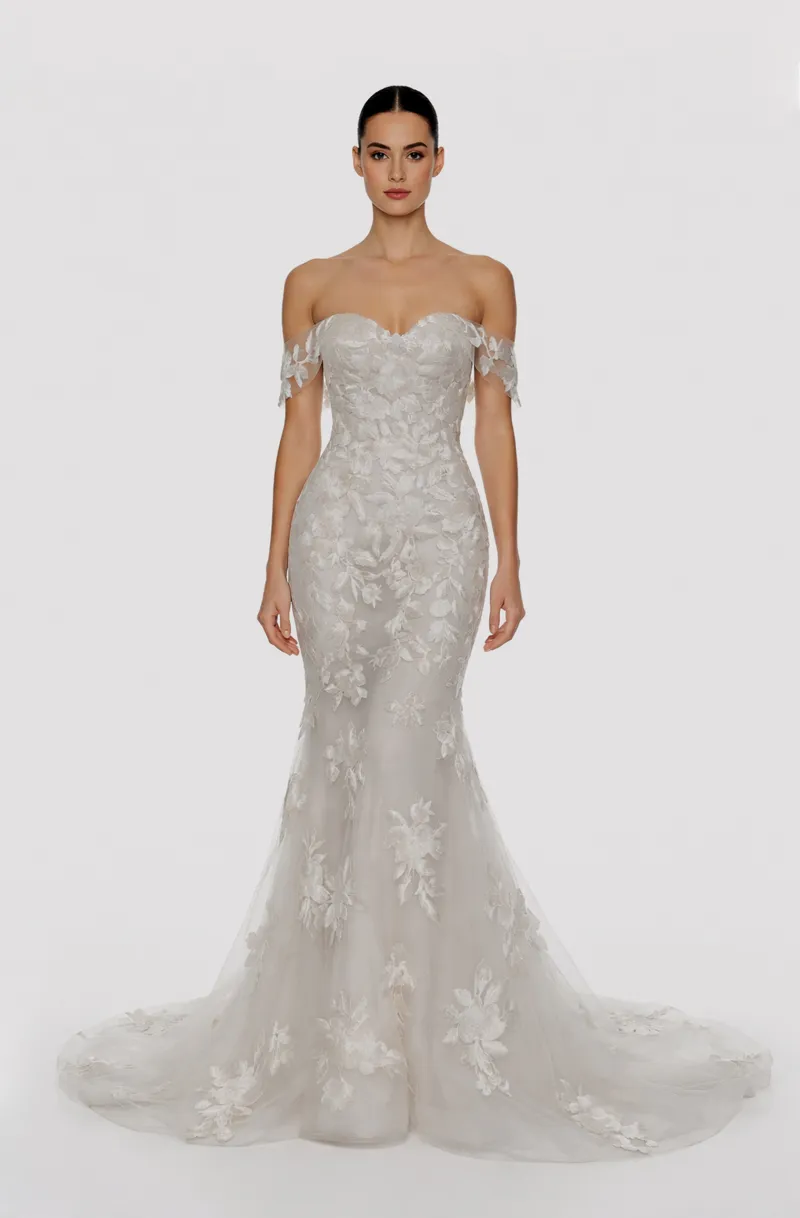 Front view of a woman in an Off-white tulle, off-shoulder sleeved mermaid gown embellished with cascading laces 9, image 1